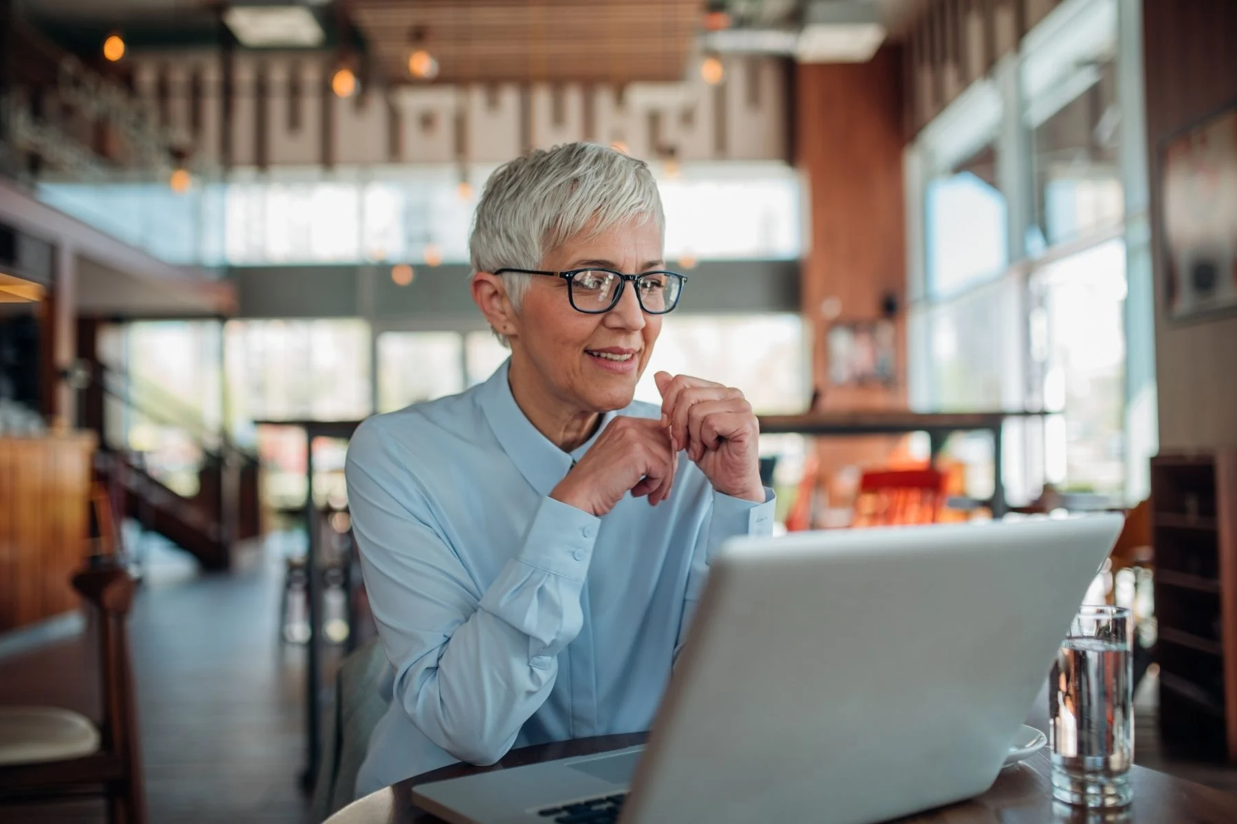 An older woman smiling at a laptop. 