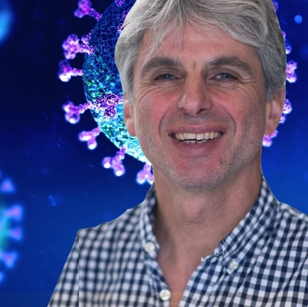A man with gray hair and a checkered shirt smiles at the camera, with a digitally rendered background showing enlarged images of viruses colored blue and purple.